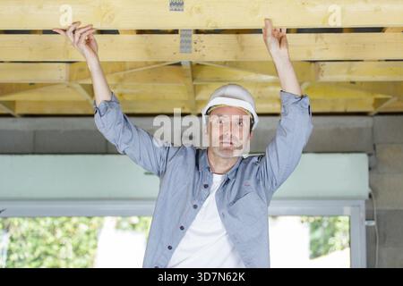a male worker checking a wood ceiling Stock Photo