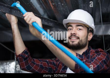 a plumber checking ceiling pipes Stock Photo