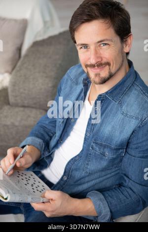 young man sitting doing a crossword puzzle Stock Photo