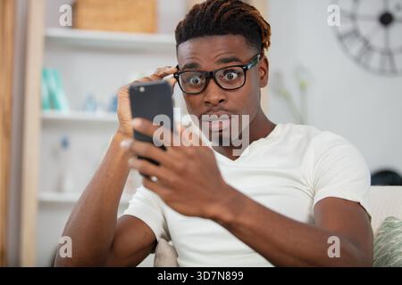 surprised happy african man holding phone Stock Photo
