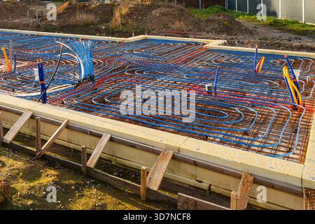 Close-up view of an underfloor heating system with colorful pipes arranged on a rebar grid, ready for concrete pouring during foundation construction Stock Photo