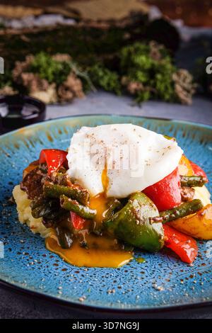 Vivid bell peppers accompany velvety polenta with runny egg yolk Stock Photo