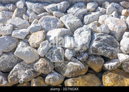 A dense collection of rough, weathered rocks forms a natural stone wall texture. Perfect for outdoor design, landscaping, or background imagery emphas Stock Photo