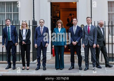 London, UK. 26th Nov, 2025. Reeves with her treasury team, including Chief Secretary to the Treasury James Murray (3rd from left), Economic Secretary Lucy Rigby (2nd from left), Lord Stockwood (1st from right) and Financial Secretary Lord Livermore (3rd from right) . Rachel Reeves, Chancellor of the Exchequer of the United Kingdom, presents the red 'budget box', her ministerial despatch box, to waiting press outside 11 Downing Street. Her Treasury team step out with her. She then departs to Parliament to deliver her much anticipated autumn budget statement. Stock Photo