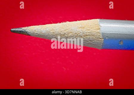 Sharpened pencil point on red background Stock Photo