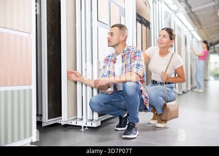 Couple examining tile samples on sliding stand in home improvement store Stock Photo
