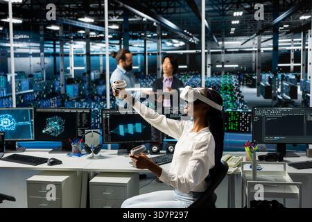 Admin in data center using AI virtual reality to troubleshoot rigs connectivity issues. IT professional using VR headset in server hub, auditing systems for vulnerabilities using neural networks Stock Photo