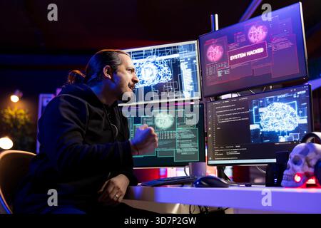 Joyous hacker celebrating after bypassing security using artificial intelligence. Evil man overjoyed after successfully penetrating firewalls, getting system hacked message on monitor Stock Photo
