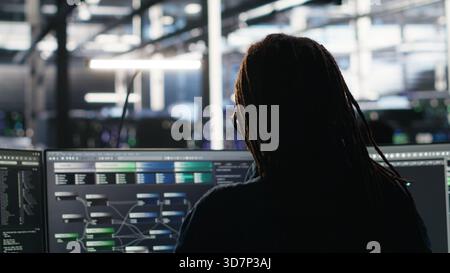 Data center engineer implements AI virtualization frameworks to optimize server clusters. Server hub IT professional doing artificial intelligence predictive analysis, camera B Stock Photo