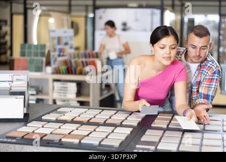 Couple browsing tile samples on display board in home improvement store Stock Photo