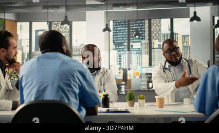 Diverse professionals collaborating in brainstorming session for healthcare. Team sharing medical expertise and diagnostic solutions for improved therapy at clinic, medical staff. Stock Photo