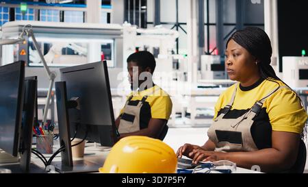 Black engineer testing solar technology at desk in renewable energy facility, focusing on software troubleshooting and performance metrics. Supports eco friendly industrial operations. Camera B. Stock Photo