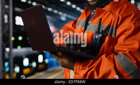 Industrial worker standing near steel machinery during construction tasks, showcasing production responsibility within the factory plant. Power in manufacturing process. Stock Photo