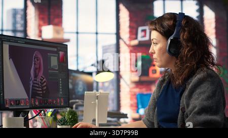Female graphic designer editing photos on a modern computer setup in agency office, using an enhancement technique. Ideal workspace for a digital design professional, photography. Camera B. Stock Photo
