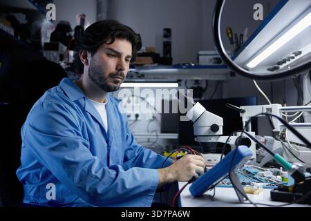 A dedicated scientist is diligently working in a modern laboratory that focuses on electronics Stock Photo