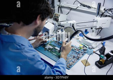 Man is repairing on electronic repair workbench equipped with circuit board Stock Photo
