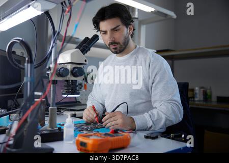 A man worker is focused on working with a motherboard Stock Photo