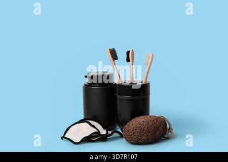 Holder with toothbrushes, bottle of cosmetic product, pumice and cotton pads on color background Stock Photo