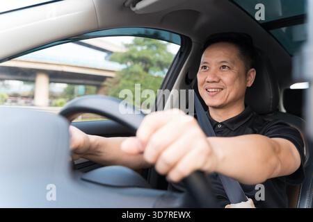 Handsome latin man drives car, wearing seatbelt, smiling. Happy driver inside automobile. Safe driving concept, road trip, traveling. Businessman taxi Stock Photo