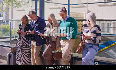 Stylish senior friends using smartphones together outdoors Stock Photo