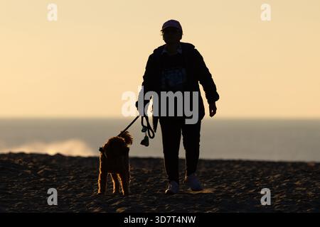 Silhouette of a Woman Walking Her Dog on Ocean Beach San Francisco at Sunset Stock Photo