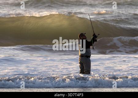 Man surf fishing in waves at Ocean Beach, San Francisco Stock Photo