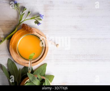 Fresh sage leaves and a cup of sage tea on a wooden table. Stock Photo