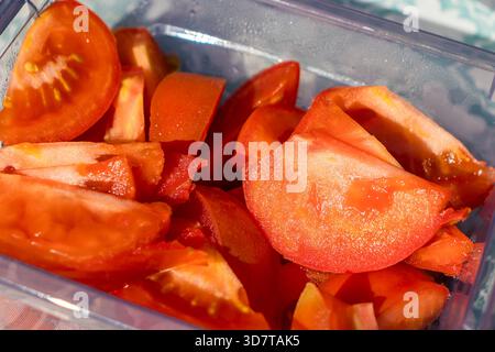 Fresh sliced tomatoes in plastic food container, close-up of red vegetable pieces. Stock Photo