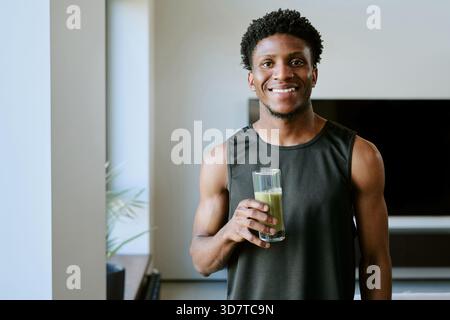 Portrait of Young Adult Black Man Smiling While Drinking Healthy Green Smoothie Stock Photo
