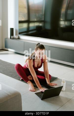 Young Caucasian Woman Practicing Morning Yoga While Watching Online Class Stock Photo