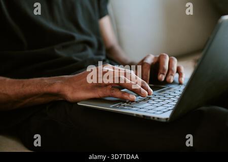 Young Adult Black Man Typing on Laptop Computer during Morning Routine Stock Photo