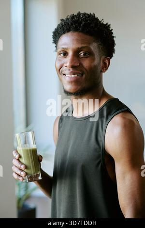 Portrait of Young Adult Black Man Smiling While Holding Healthy Morning Smoothie Stock Photo