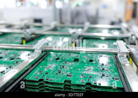 Stacks of assembled green printed circuit boards in metal rack on cart inside smart automated electronics factory Stock Photo