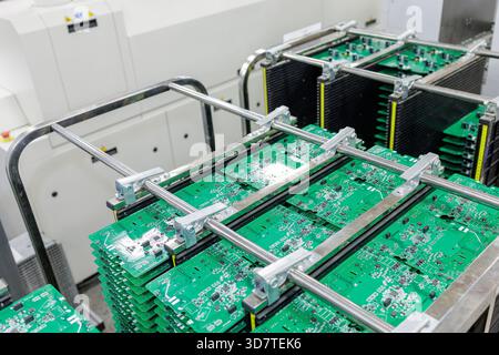 Stacks of green printed circuit boards stored in metal racks inside modern automated electronics manufacturing plant Stock Photo