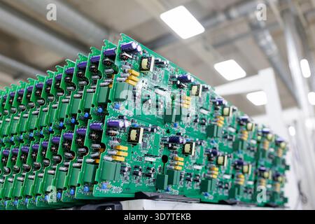 Rows of assembled green printed circuit boards with power electronics components in modern automated manufacturing plant Stock Photo