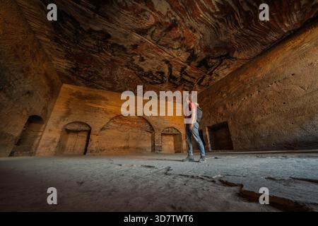 Tourist admiring colorful sandstone ceiling inside Royal Tomb, Petra, Jordan Stock Photo