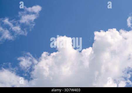A serene image of fluffy white clouds set against a vibrant blue sky, evoking calmness and tranquility. Stock Photo