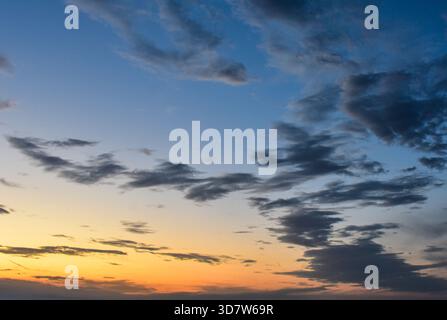 The sky glows with warm sunset tones as soft clouds absorb magical hues, creating a stunning and calming afternoon impression. Stock Photo