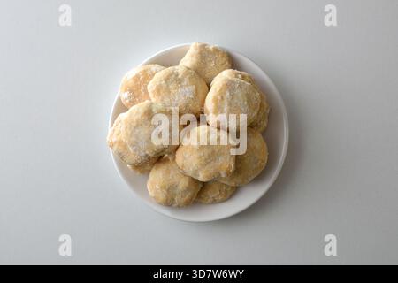 Macro detail of a stack of sugar cookies on a white ceramic plate in the center of the image, isolated on a white table. Top view. Stock Photo