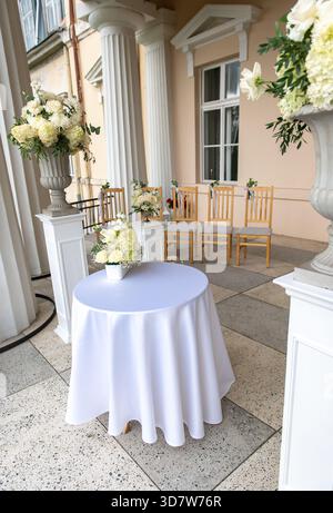 Wedding ceremony chairs decorated with white flowers arranged on a classical terrace in Latvia. Stock Photo