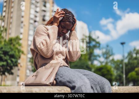 Young black woman is distraught while using her smartphone. Stock Photo