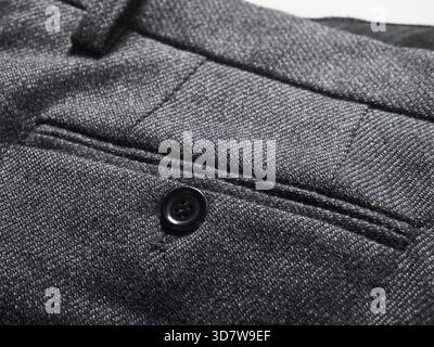 Close-up of a textured gray fabric with a black button and detailed stitching. Stock Photo