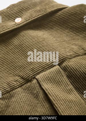 Olive green ribbed fabric texture with button detail on textured surface Stock Photo