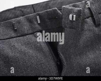 Close-up of a black and white herringbone pattern trouser waistband with metal hooks. Stock Photo