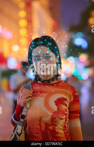 Woman on street with digital facial recognition grid and blurred colorful lights. Shanghai, China Stock Photo