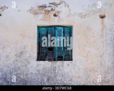 Vibrant blue shutters in concrete wall with peeling paint Stock Photo