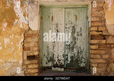 Pale green door in limestone wall with crumbling plaster Stock Photo