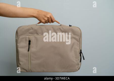 Hand Holding A Textured Laptop Bag Against A Plain Background With Studio Lighting Stock Photo