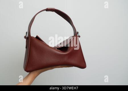 Handheld Textured Deep Red Leather Shoulder Bag With White Stitching And Silver Hardware On White Background Stock Photo