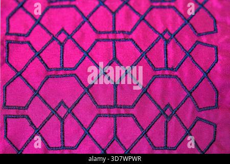 Close-up of embroidered geometric pattern on bright pink fabric. Stock Photo